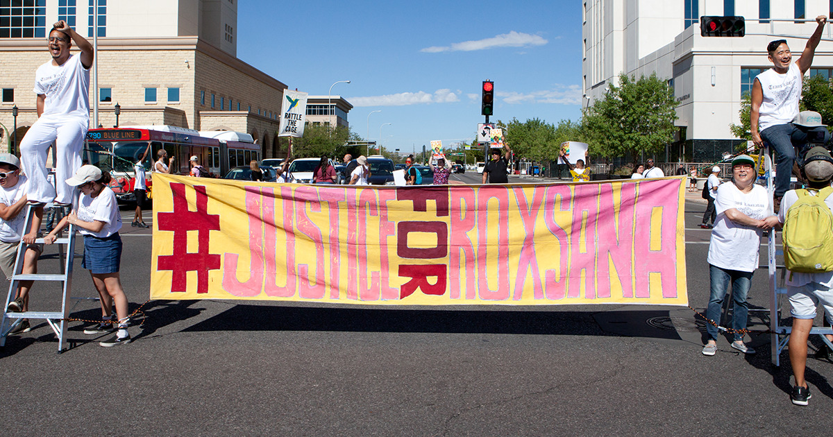 Protestors hold a large #JusticeForRoxsana banner