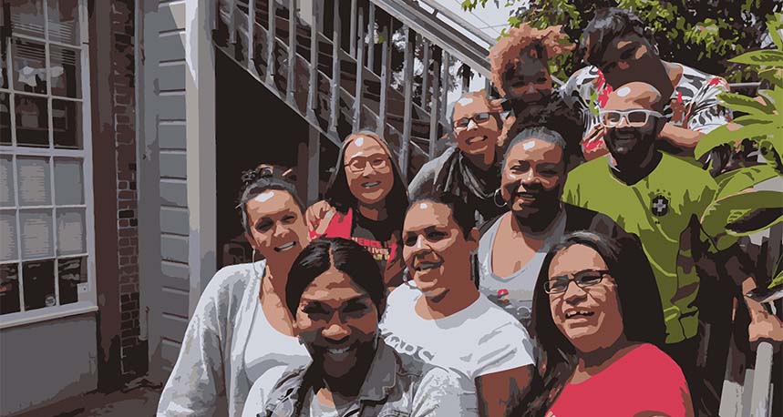 A group of 8 people, all smiling and joyful, standing on a set of stairs.